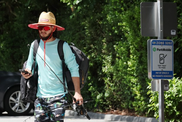 Mateo Solaert uses his phone to pay for parking at South Inlet Park on Sunday, June 28, 2026. (Joe Cavaretta/South Florida Sun Sentinel)