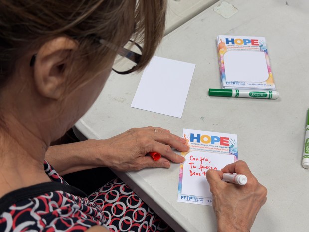 An Hispanic Heritage Chamber of Commerce volunteer writes a note to be included with hygiene kits heading to Venezuela at Food For The Poor's Coconut Creek headquarters. (Food For The Poor/Courtesy)