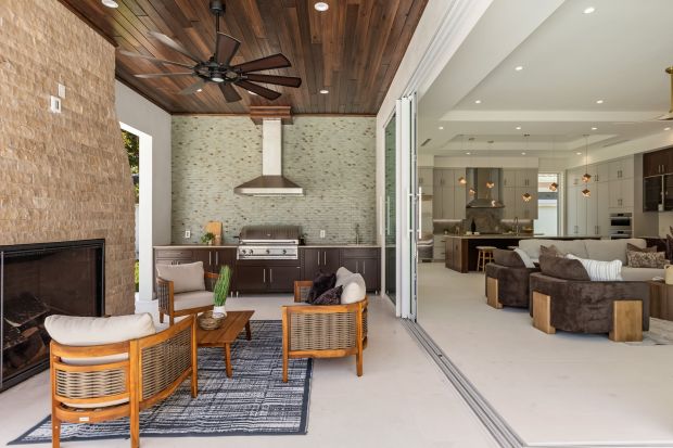 The expansive screened lanai was designed for year-round enjoyment and entertaining, featuring a summer kitchen and fireplace that seamlessly extend the living experience outdoors.(Mohsin at Florida Home Photo)