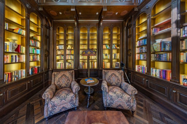 The mansion has two home offices and a library, highlighted by custom dark-wood cabinetry and a cozy fireplace. (Photo by Harvey Smith)
