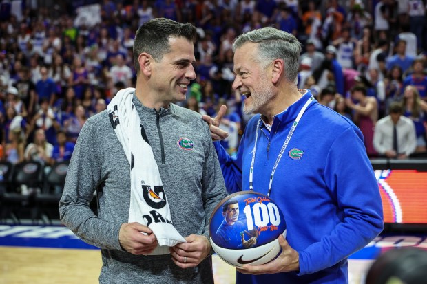 Florida head coach Todd Golden, left, (L-R) receives a game ball from athletic director Scott Stricklin to celebrate Golden's 100th win March 3, 2026 after the Gators beat Mississippi State 108-74 at the Stephen C. O'Connell Center in Gainesville. (Photo by James Gilbert/Getty Images)
