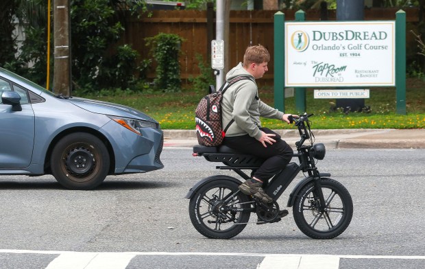An Edgewater High student rides an e-bike on Par Avenue after school, Monday, April 20, 2026. On Tuesday, the Orange County School Board will met to vote on new restrictions to e-bikes and e-scooters for the upcoming school year. (Joe Burbank/Orlando Sentinel)