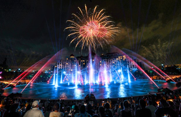 Guests watch the debut of the first nighttime finale fireworks show at Universal Epic Universe in Orlando, Tuesday, July 7, 2026. With the Helios Grand Hotel as a backdrop, the "Universal Celestial Goodnight" show launches at Cosmos Lagoon and features a highly synchronized production of dancing water fountains and light with music and fireworks. (Joe Burbank/Orlando Sentinel)