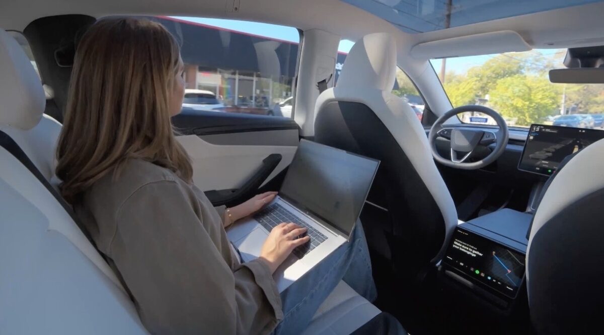 Tesla Robotaxi interior with passenger on laptop