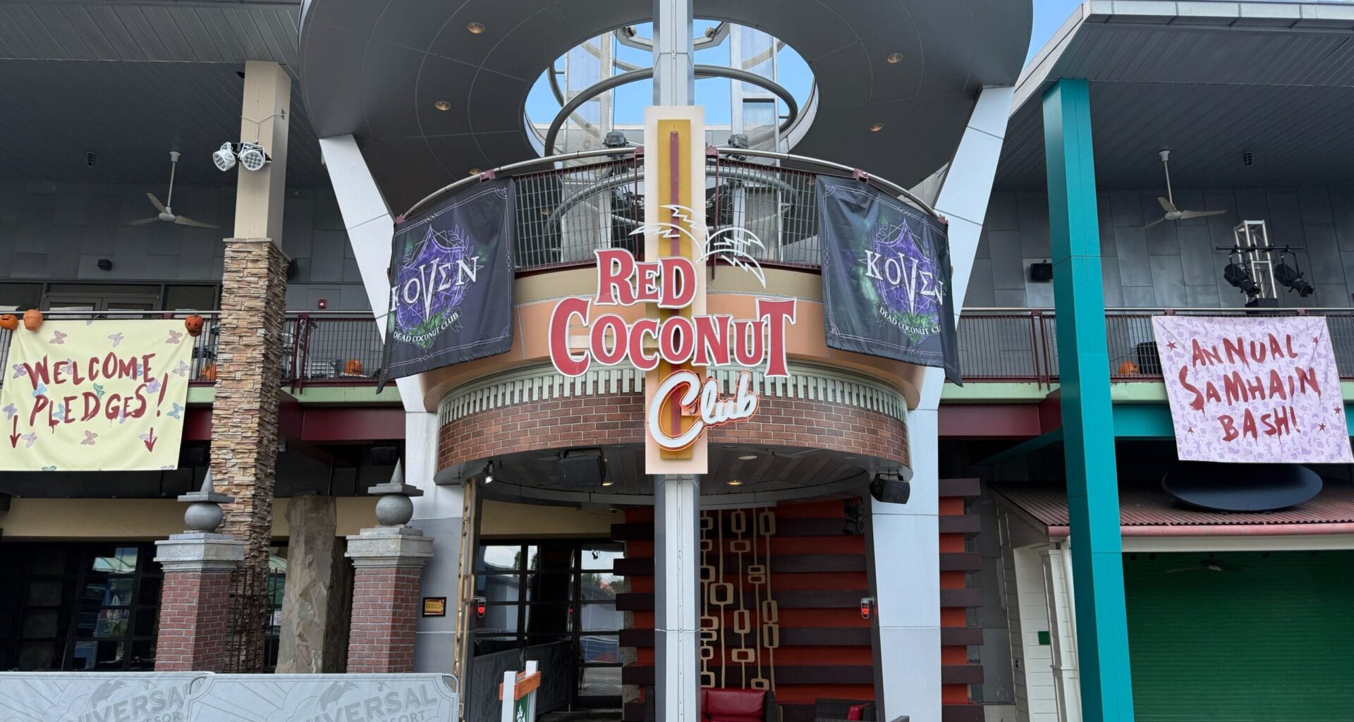 Entrance of the Red Coconut Club styled for HHN, featuring banners for “Annual Samhain Bash!” and “Welcome Pledges!”