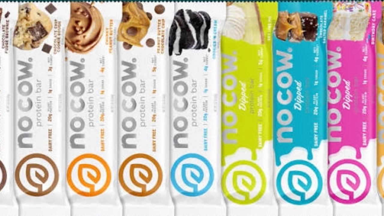 Assorted No Cow plant-based protein bars and dipped protein bars in multiple flavors displayed in branded retail packaging.