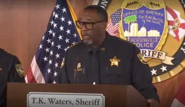 Sheriff T.K. Waters standing at a lectern as he announces the arrest of a police officer.
