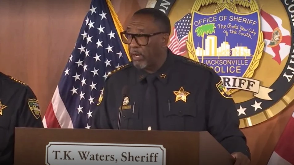 Sheriff T.K. Waters standing at a lectern as he announces the arrest of a police officer.