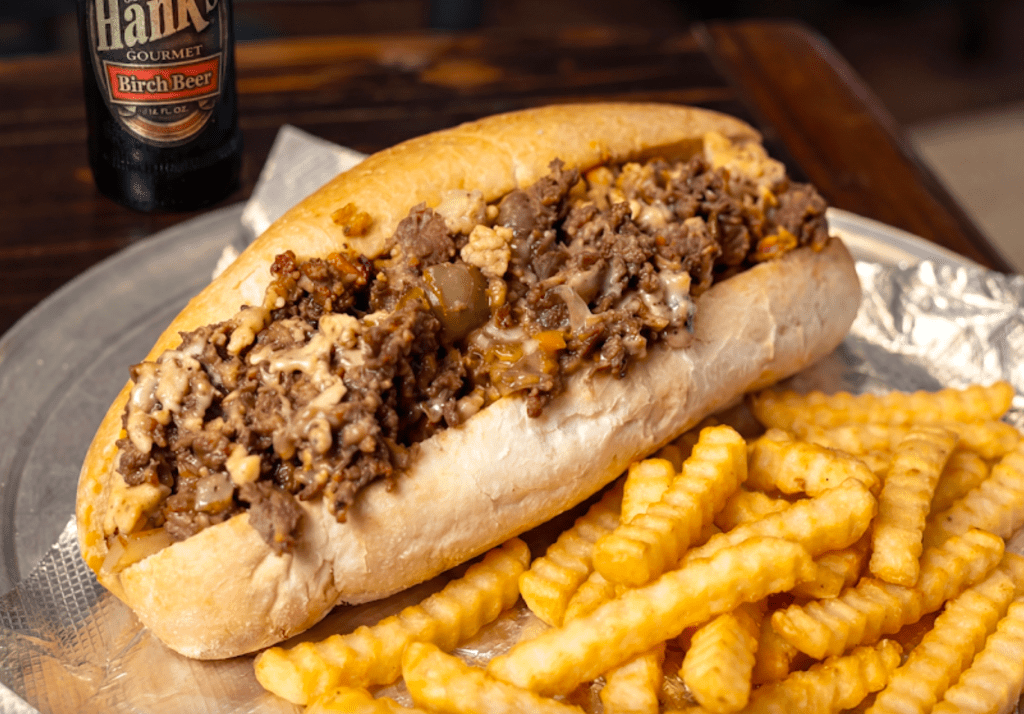 a cheesesteak next to fries