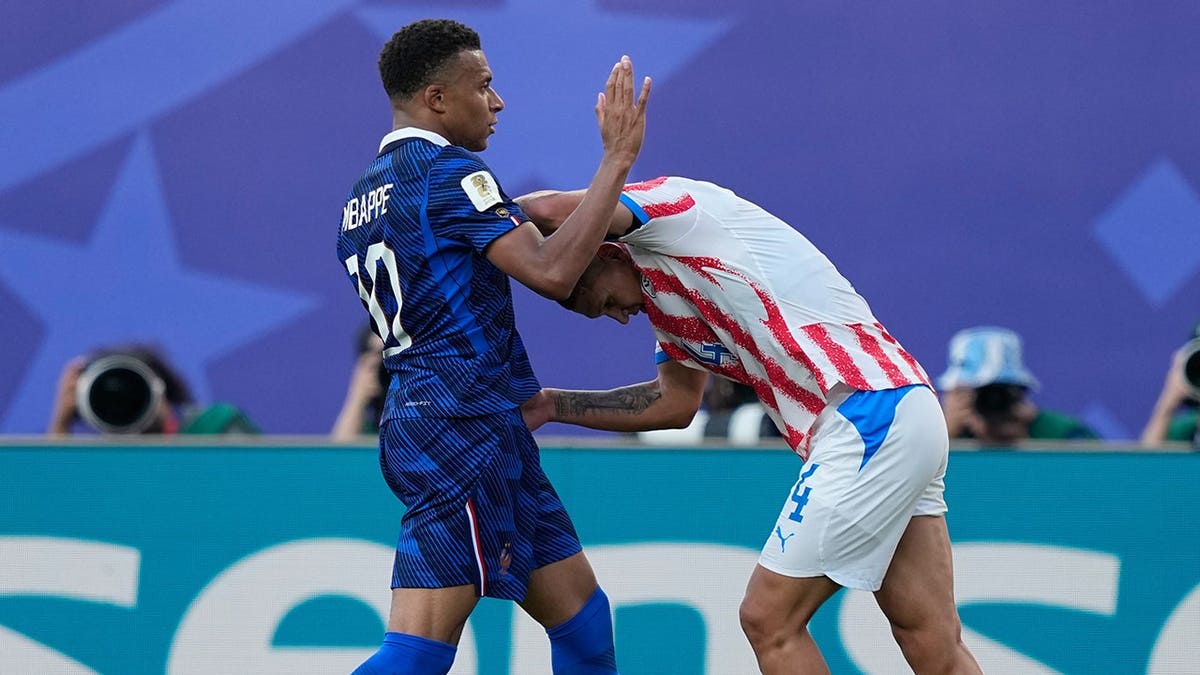 France's Kylian Mbappe and Paraguay's Juan Jose Caceres scuffle during a World Cup round of 16 match.