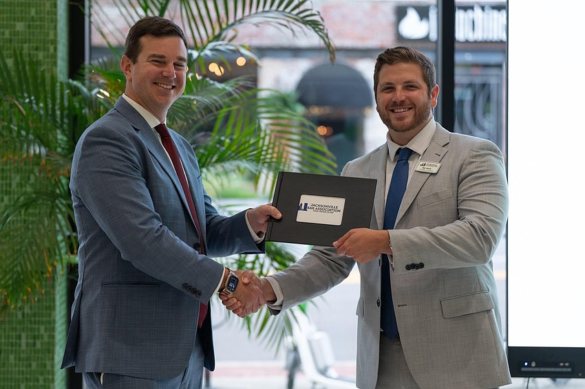 Young Lawyers Section 2026-27 President Matt Borello, right, presented a “year-in-review” photo album gift from the board to outgoing president Adam Prom. Young Lawyers Section 2026-27 President Matt Borello, right, presented a “year-in-review” photo album gift from the board to outgoing president Adam Prom.