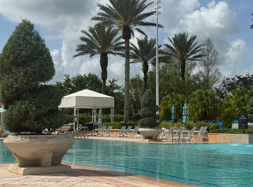 rizt carlton orlando outdoor pool with lounge chairs, cabana, and palm trees under a cloudy sky rizt carlton orlando outdoor pool with lounge chairs, cabana, and palm trees under a cloudy sky