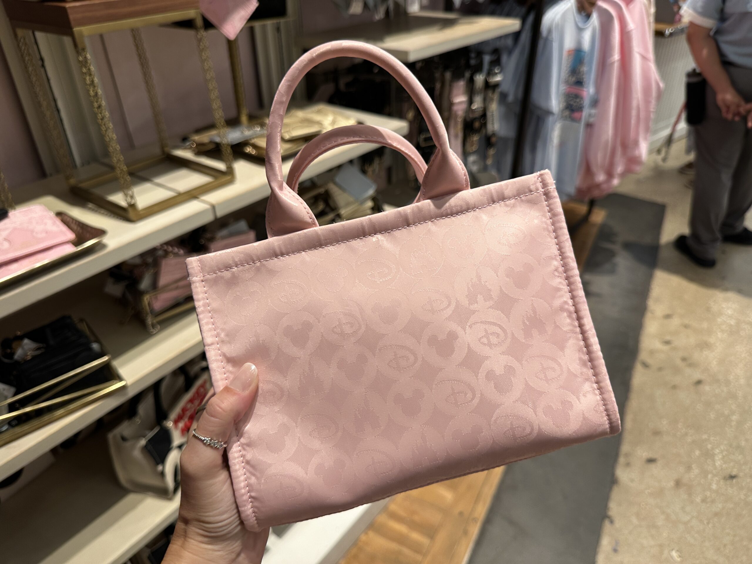 One of the bags you can purchase is a light pink tote with a repeating circular pattern with Disney iconography on it. The circles have a pattern of Disney