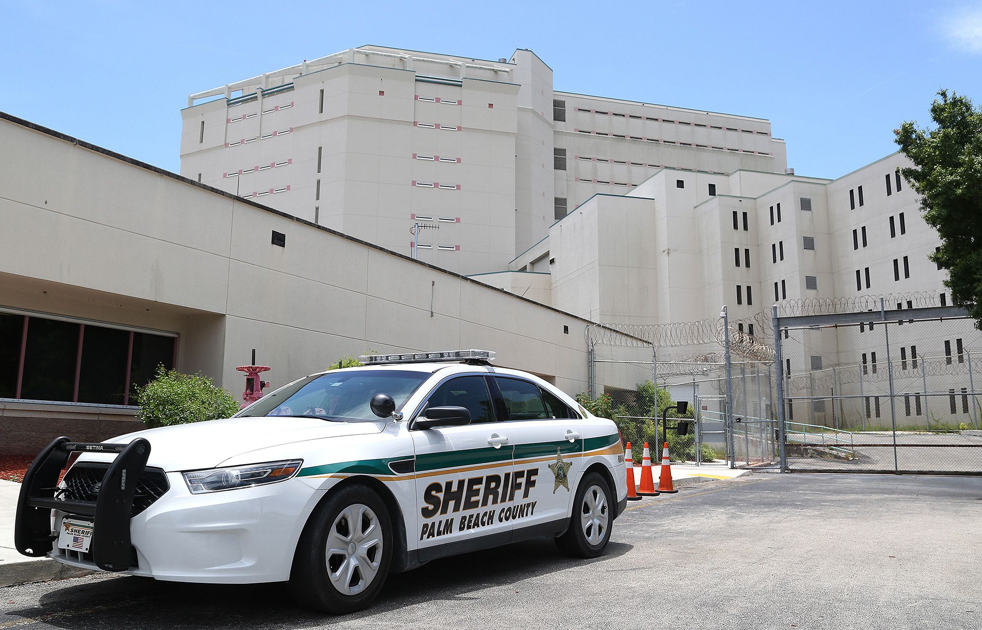 A photo shows a car with the label "Palm Beach County Sheriff" parked in front of a gray building.