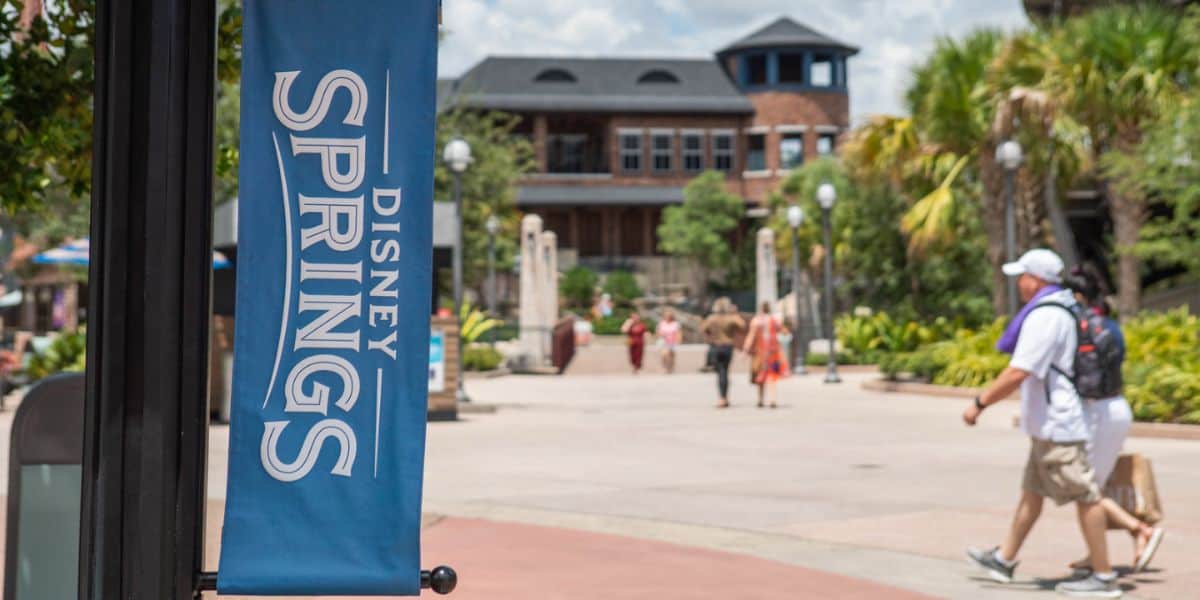 Guests walk past a Disney Springs sign