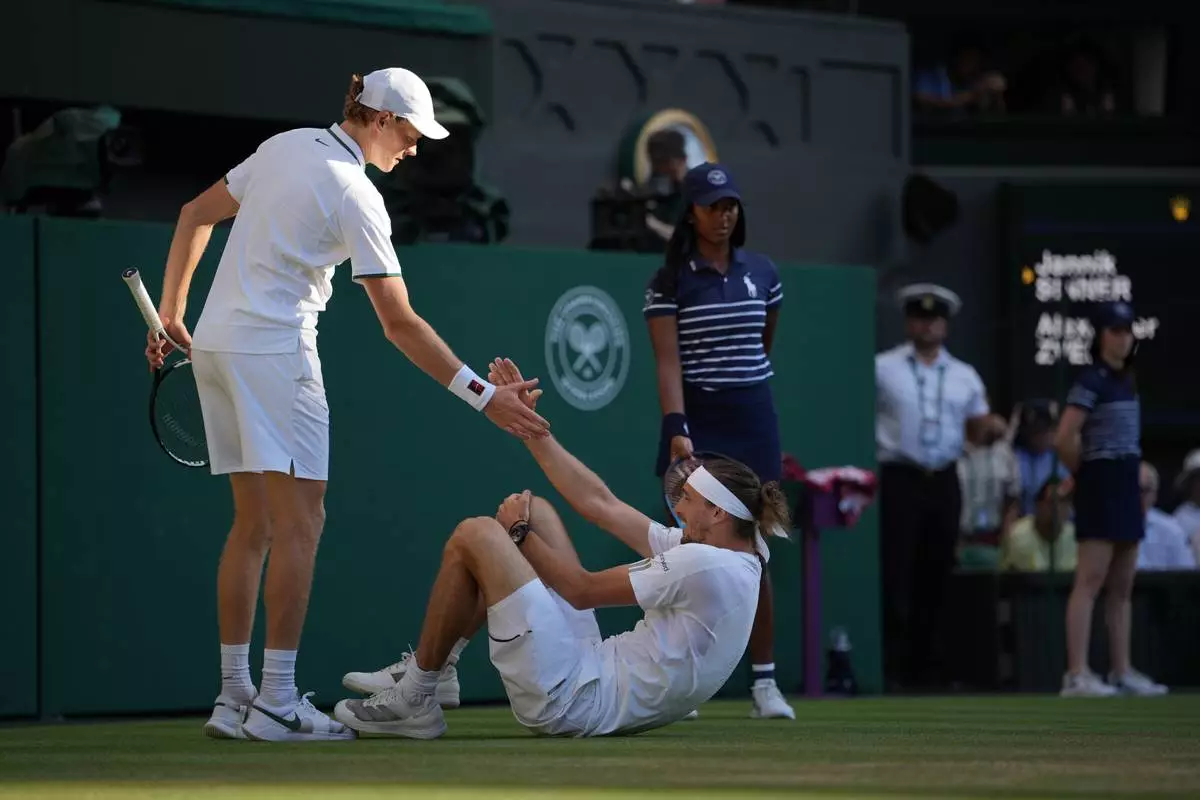 Jannik Sinner of Italy, left helps up Alexander Zverev of Germany who fell during the men's singles final at Wimbledon Tennis Championships in London, Sunday, July 12, 2026. (AP Photo/Kin Cheung)