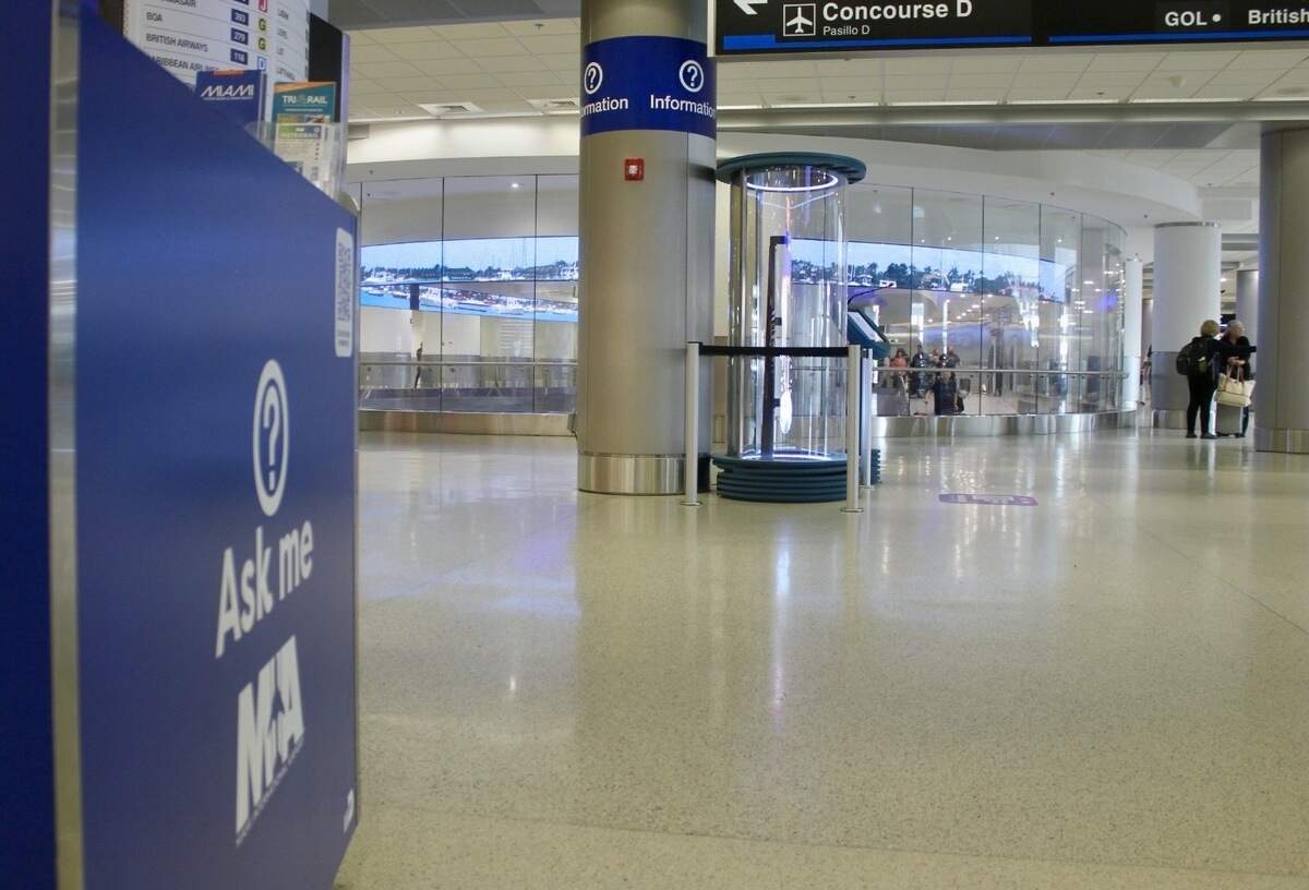 The distance between a volunteer ‘Ask Me’ information desk and an AI hologram assistant near concourse D in Miami International Airport on July 1, 2026.