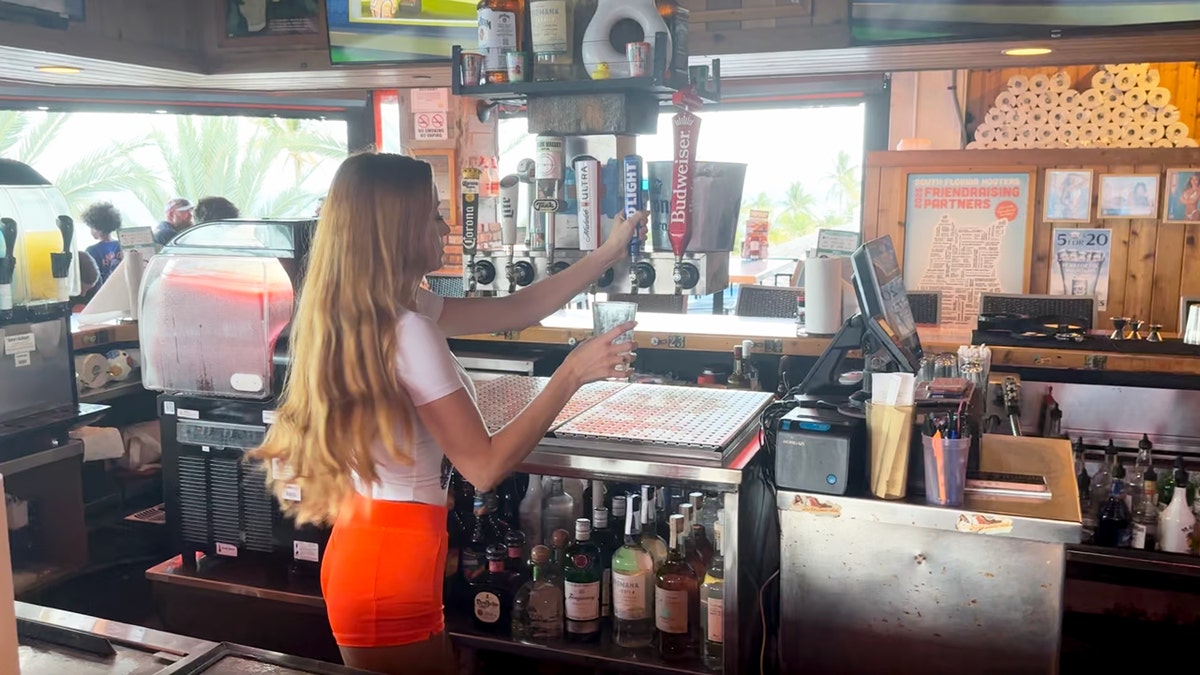 A Hooters bartender pours a beer from a tap.