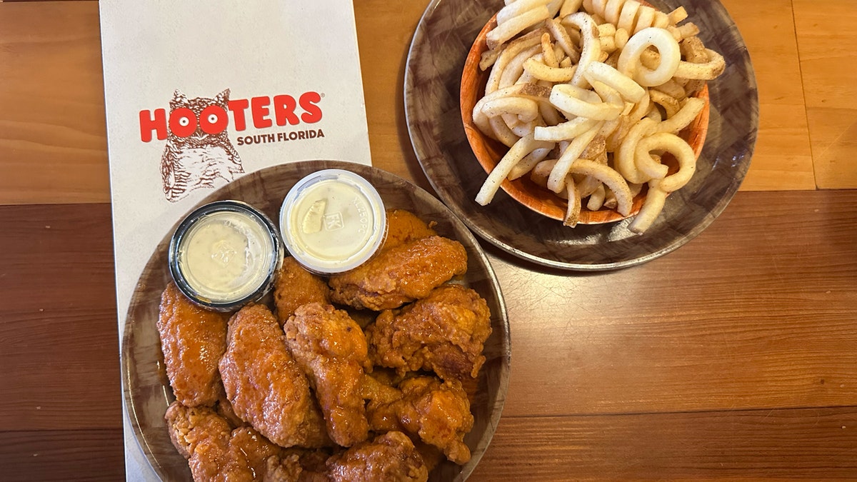 Hooters chicken wings and curly fries are pictured along with a restaurant menu.
