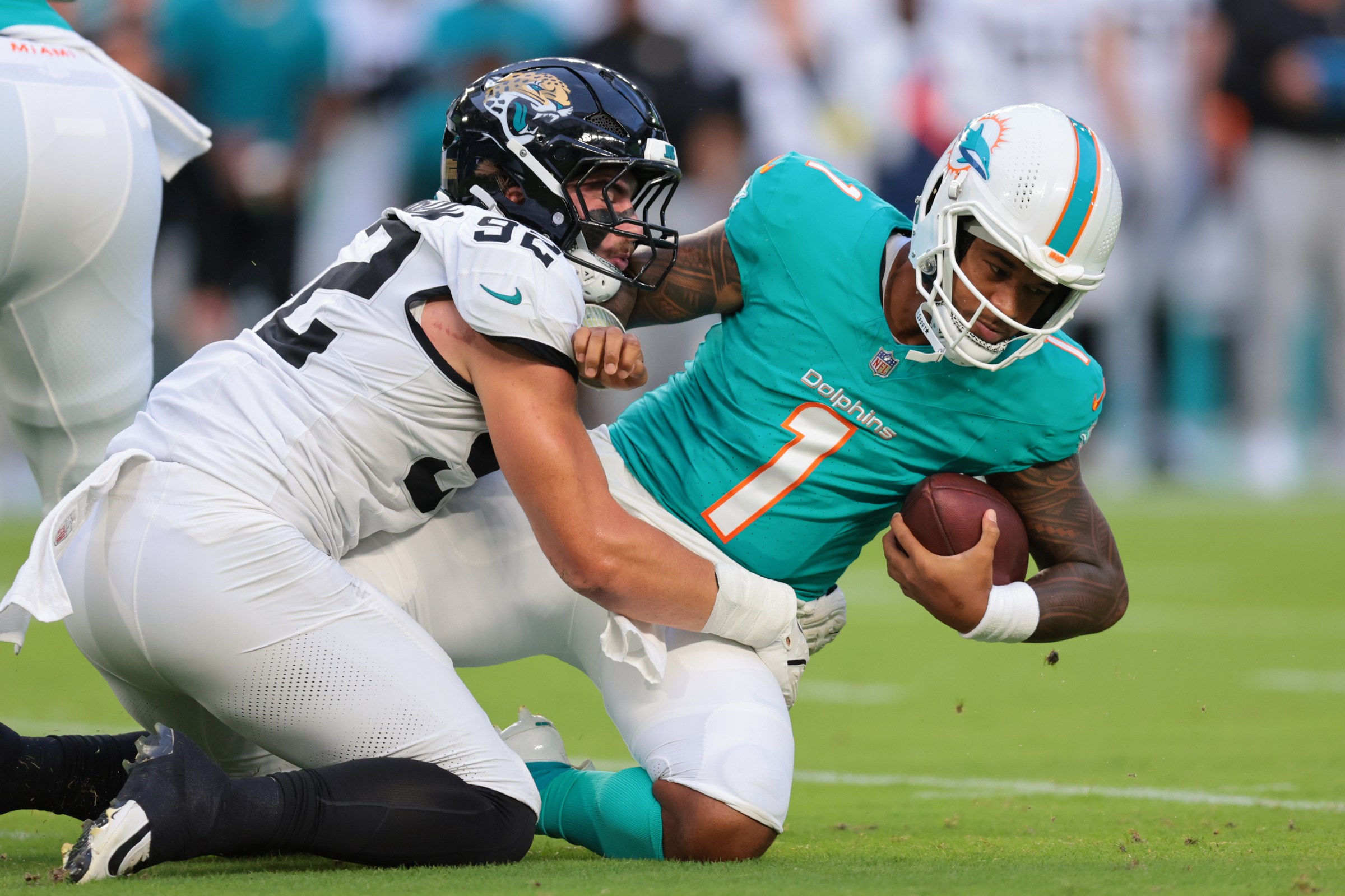 Aug 23, 2025; Miami Gardens, Florida, USA; Jacksonville Jaguars defensive end Danny Striggow (92) tackles Miami Dolphins quarterback Tua Tagovailoa (1) during the first quarter at Hard Rock Stadium. Mandatory Credit: Sam Navarro-Imagn Images
