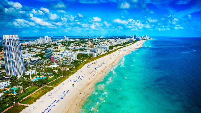 A drone view of the coastline along Miami Beach, Florida, with the sea and sand and hotels lining the beaches