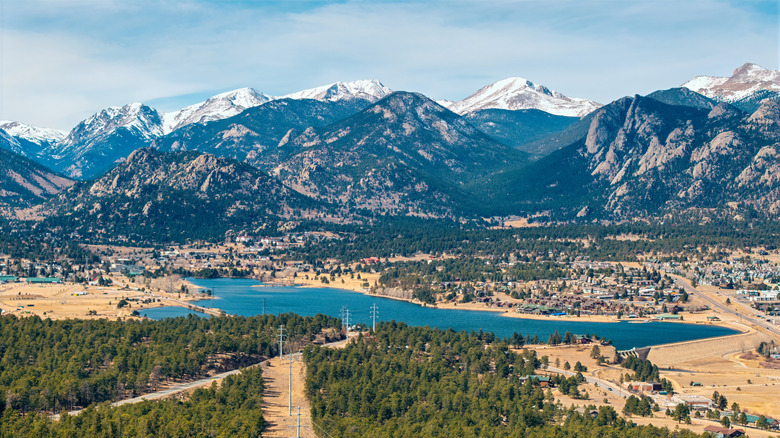 A town hugs a lake below the Rocky Mountains in Colorado