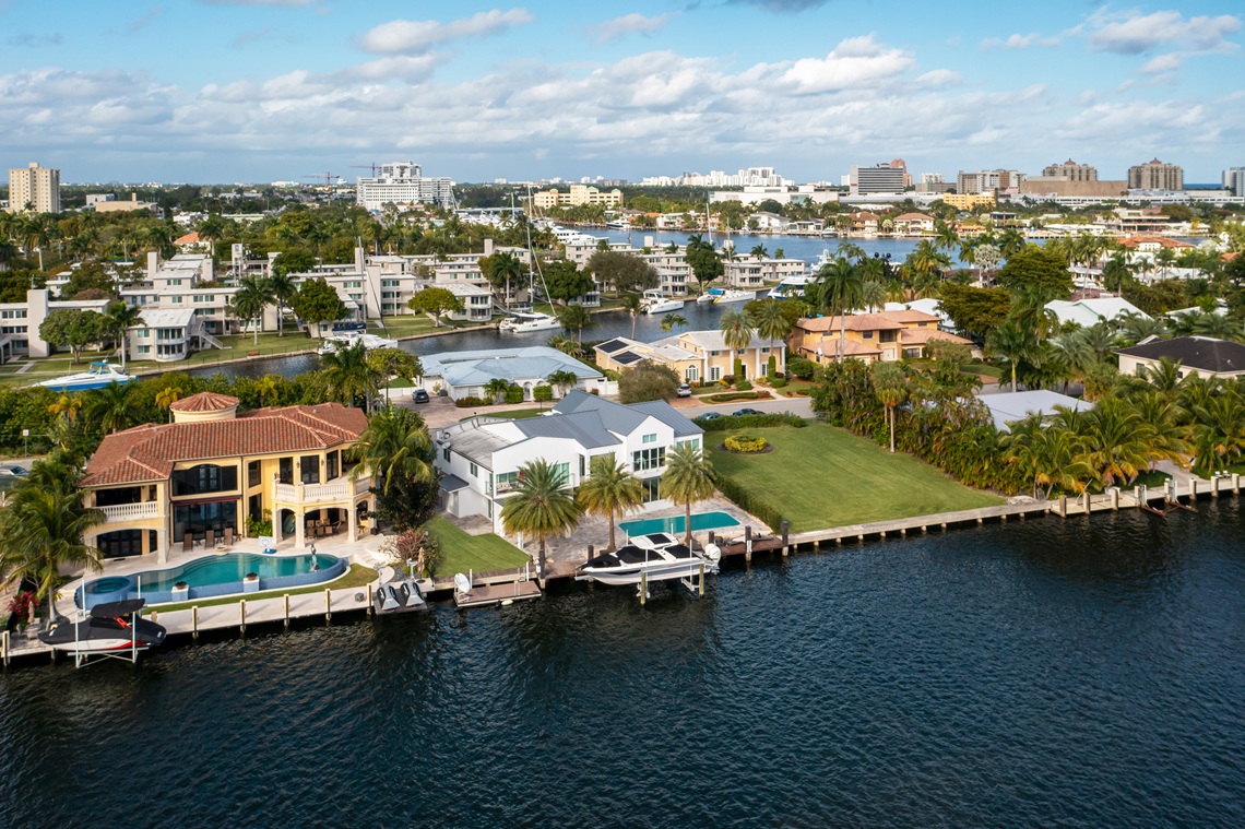 Aerial drone shot of sunrise key neighborhood in Fort Lauderdale, you can see the Rio Barcelona canal, modern and luxury houses, blue sky boats and tropical climate