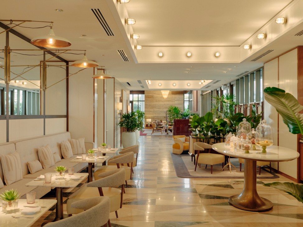 Honey Fitz café and champagne bar interior with beige seating, copper pendant lights, and tropical plants
