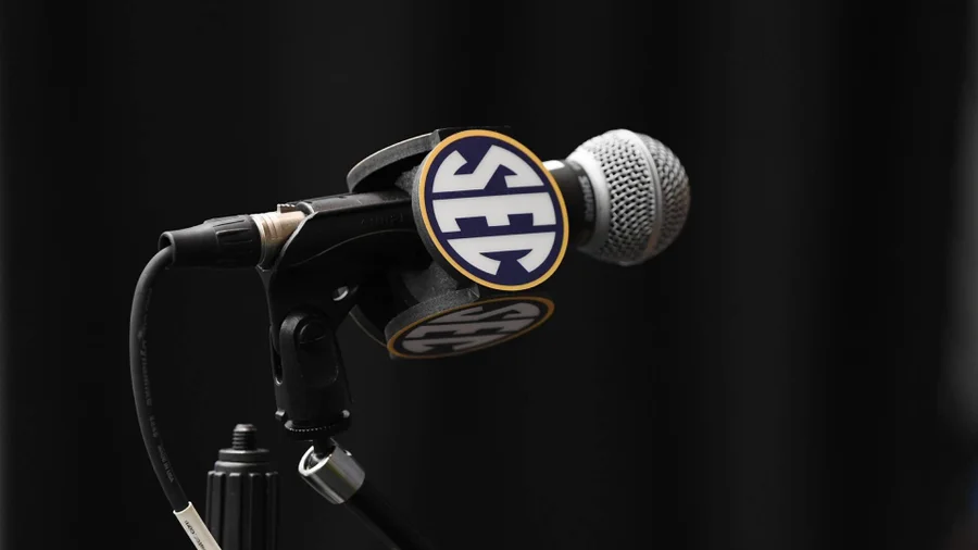 SEC Football Media Days podium stands in front of a large SEC-branded backdrop featuring a blue football helmet at the JW Marriott Tampa Water Street.