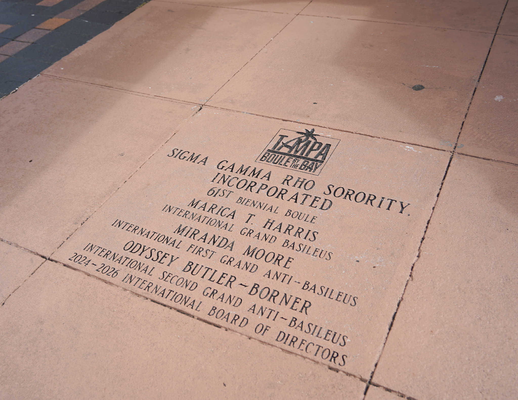 A close-up view of the engraved stone paver on the Tampa Riverwalk reading "Sigma Gamma Rho Sorority, Incorporated 61st Biennial Boule" along with the names of sorority leadership.