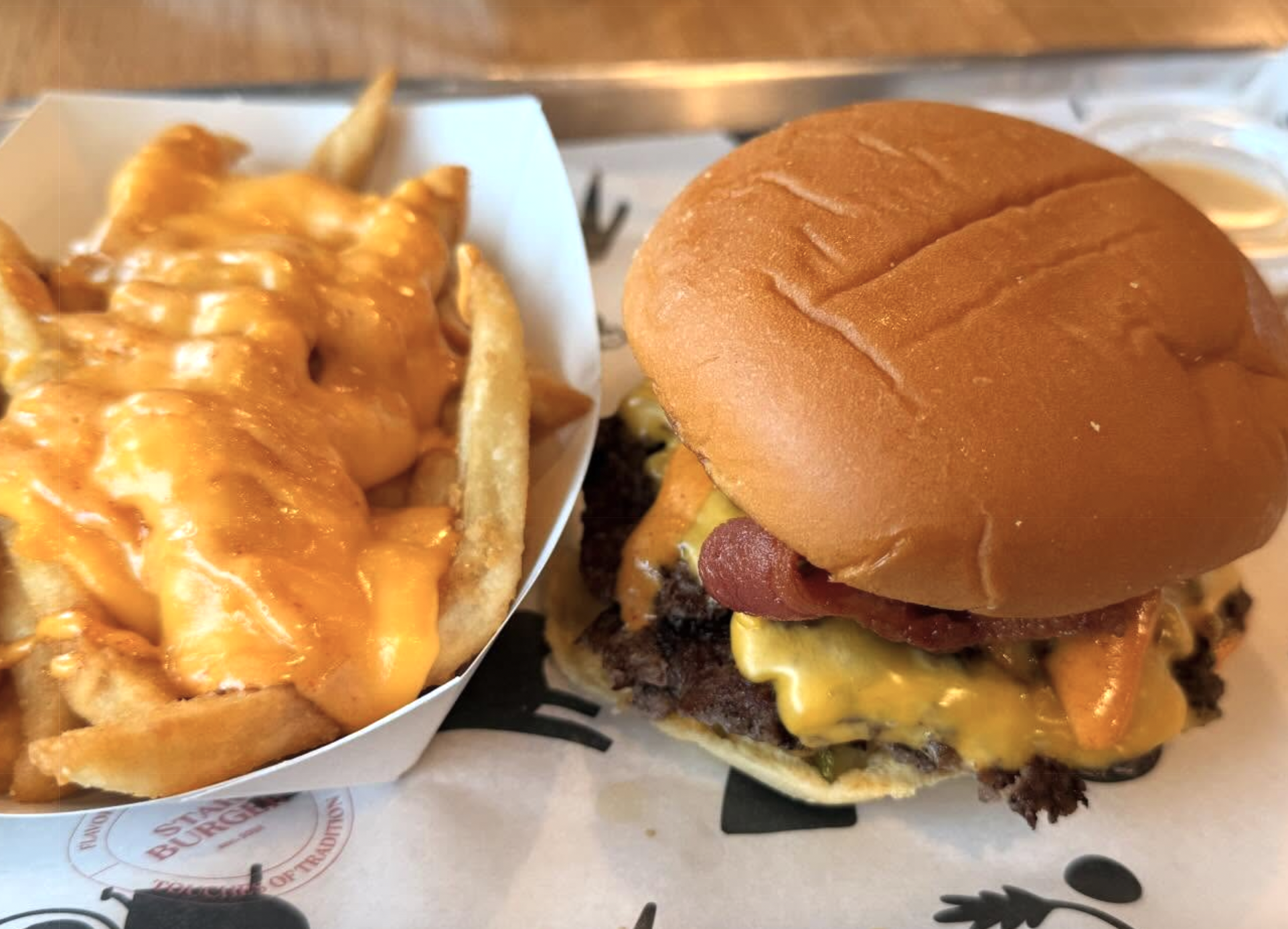 a cheese burger and a side of fries smothered in yellow cheese