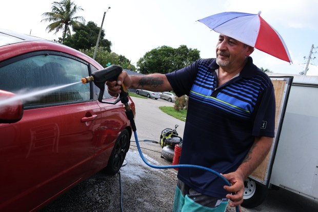 Abraham Medina wears his portable shade hat as he washes his car in Oakland Park Wednesday, July 8, 2026. The National Weather Service on Wednesday issued a heat advisory from 11 a.m. to 6 p.m. across Miami-Dade, Broward and Palm Beach counties, and warned that intense conditions are likely to persist into next week.(Joe Cavaretta/South Florida Sun Sentinel)