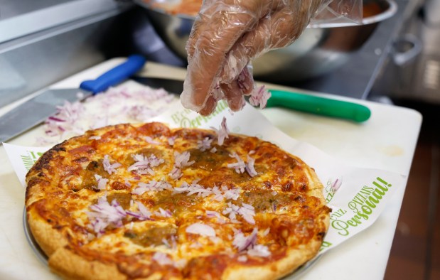 Naresh (Rush) Patel adds onions a Signature Pav Bhaji Pizza at Singas Famous Pizza on 1790 West Sand Lake Road in Orlando, on Wednesday, July 22, 2026. (Ricardo Ramirez Buxeda/ Orlando Sentinel)