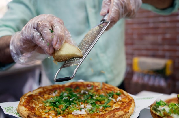 Naresh (Rush) Patel grates fresh ginger on a Signature Chana Masala Pizza at Singas Famous Pizza on 1790 West Sand Lake Road in Orlando, on Wednesday, July 22, 2026. (Ricardo Ramirez Buxeda/ Orlando Sentinel)