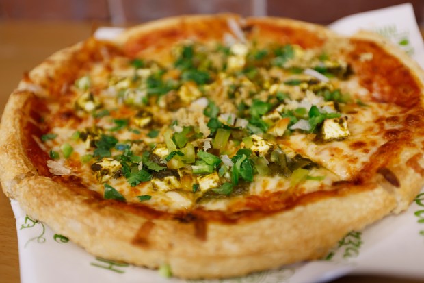 Signature Palak Paneer Pizza ("Our signature cheese pizza topped with creamy spinach (palak) and soft paneer cubes, seasoned with aromatic spices. Finished with raw onion and diced bell peppers for added freshness and crunch.") from Singas Famous Pizza on 1790 West Sand Lake Road in Orlando, on Wednesday, July 22, 2026. (Ricardo Ramirez Buxeda/ Orlando Sentinel)