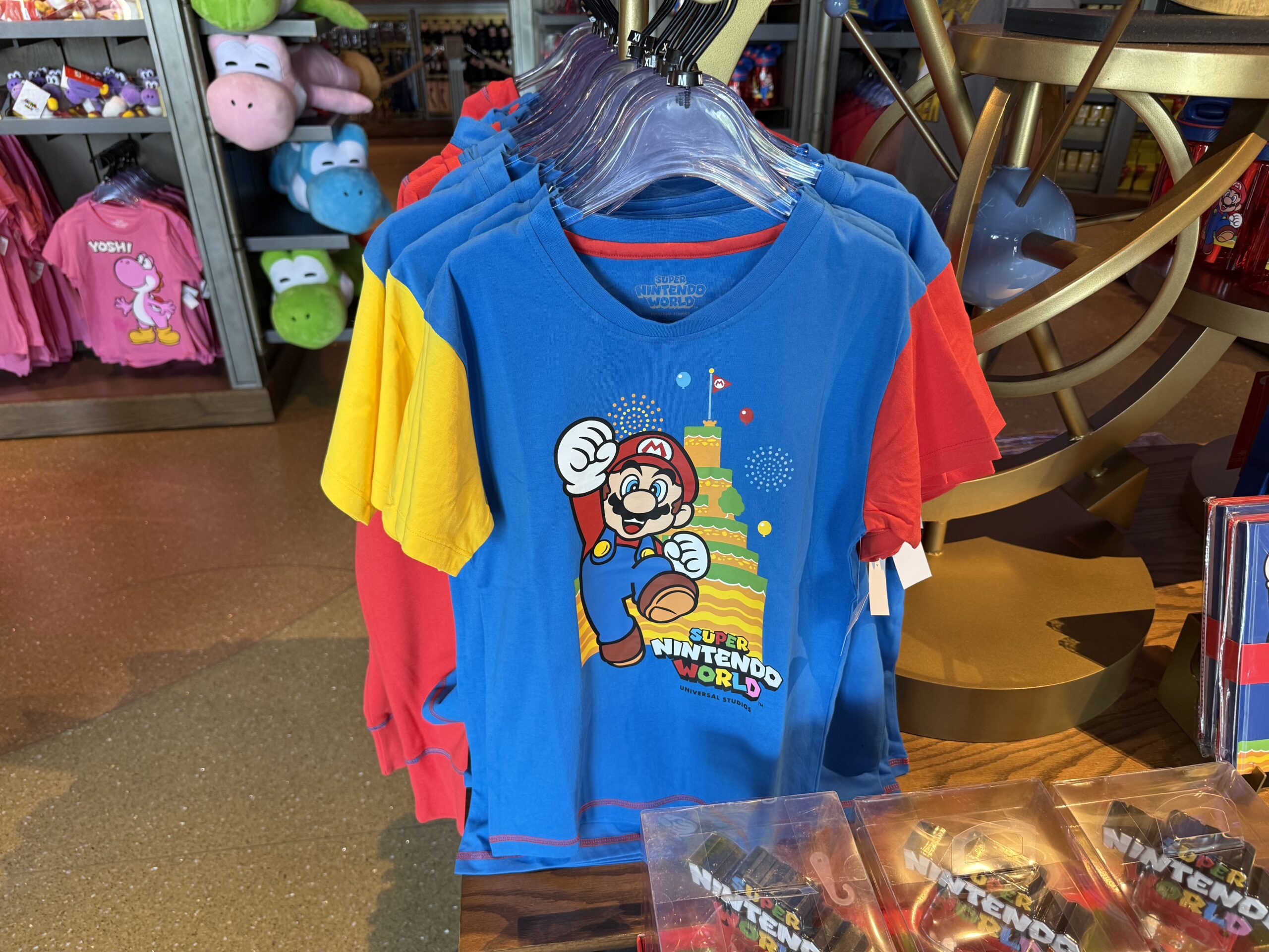 Another shirt for youth is blue with red and yellow sleeves, and has Mario with Mount Beanpole on the front.
