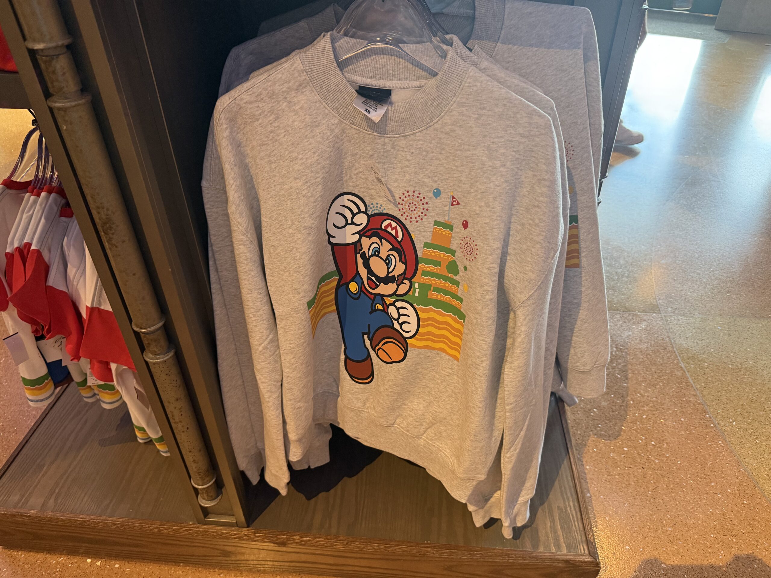 The anniversary design along with the Super Nintendo World are also on the front and back of this light-gray pullover sweatshirt for adults.