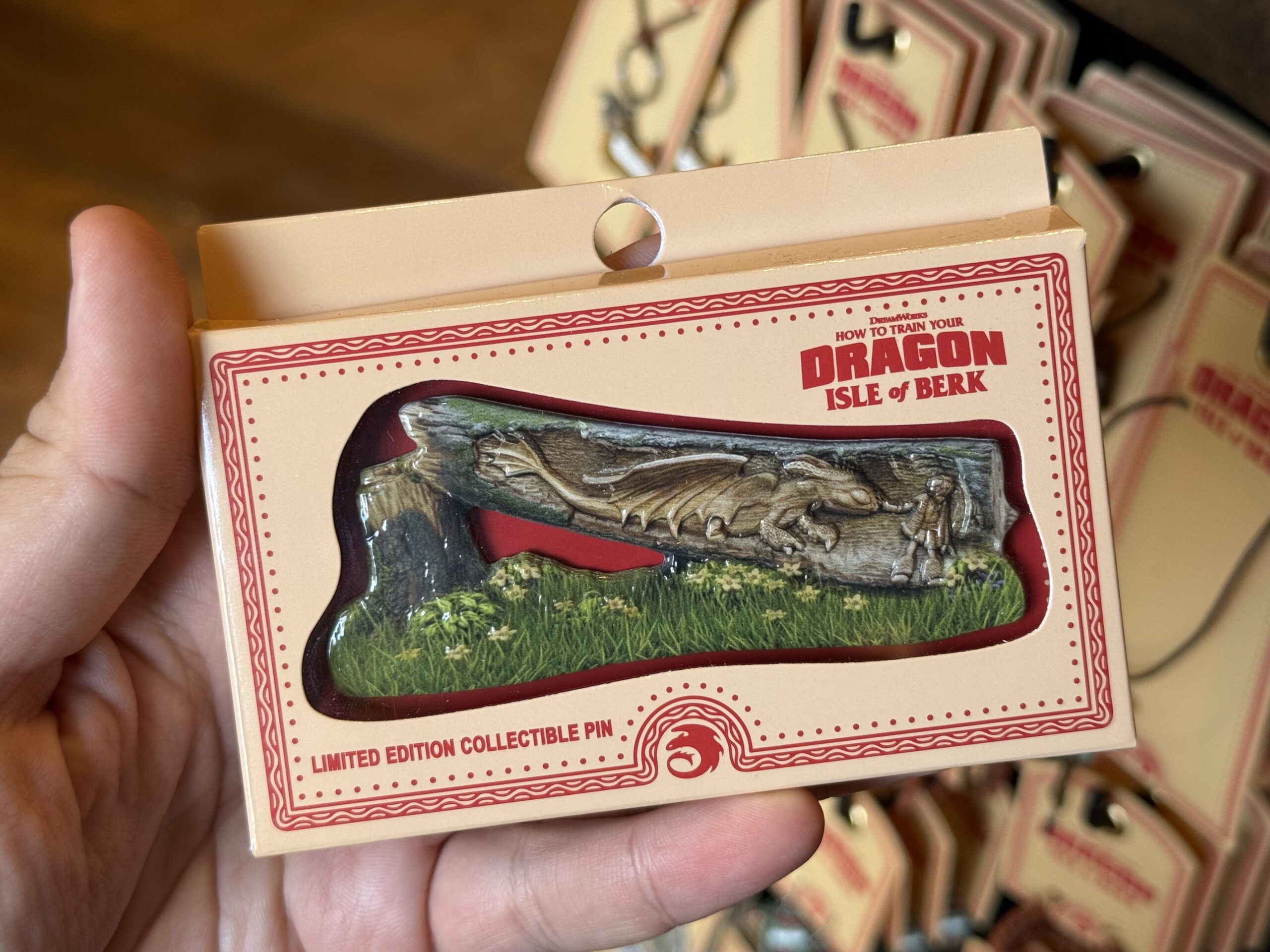 This limited edition collectible pin features a chopped down tree with Hiccup and Toothless carved inside. It comes in a beige box with red accents.