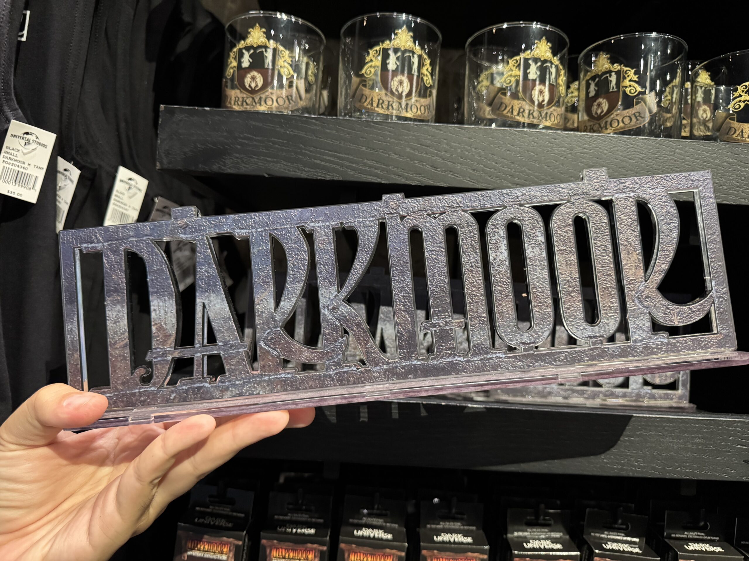 This plastic sign is a replica of the village's real sign. It has a finish resembling metal and holes in the back for hanging. It also has a flat base so it can stand up on its own.