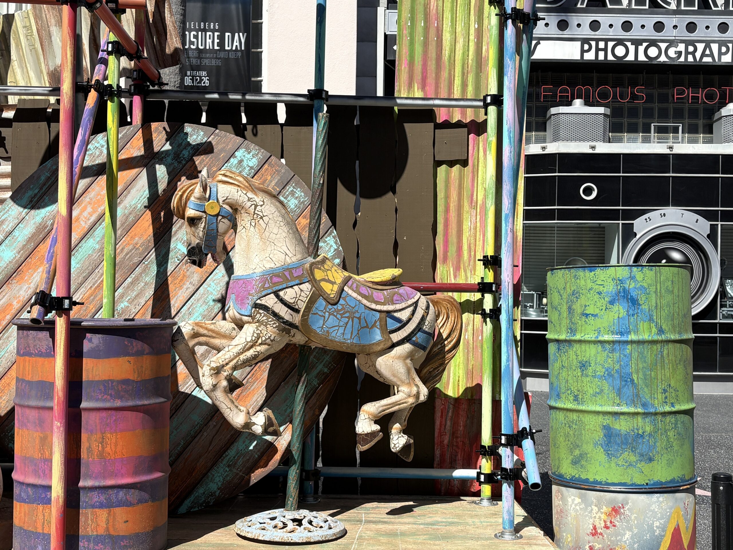 There's a two-headed swan boat — maybe from a Tunnel of Love attraction — and a carousel horse. Around them are colorful barrels and scaffolding.