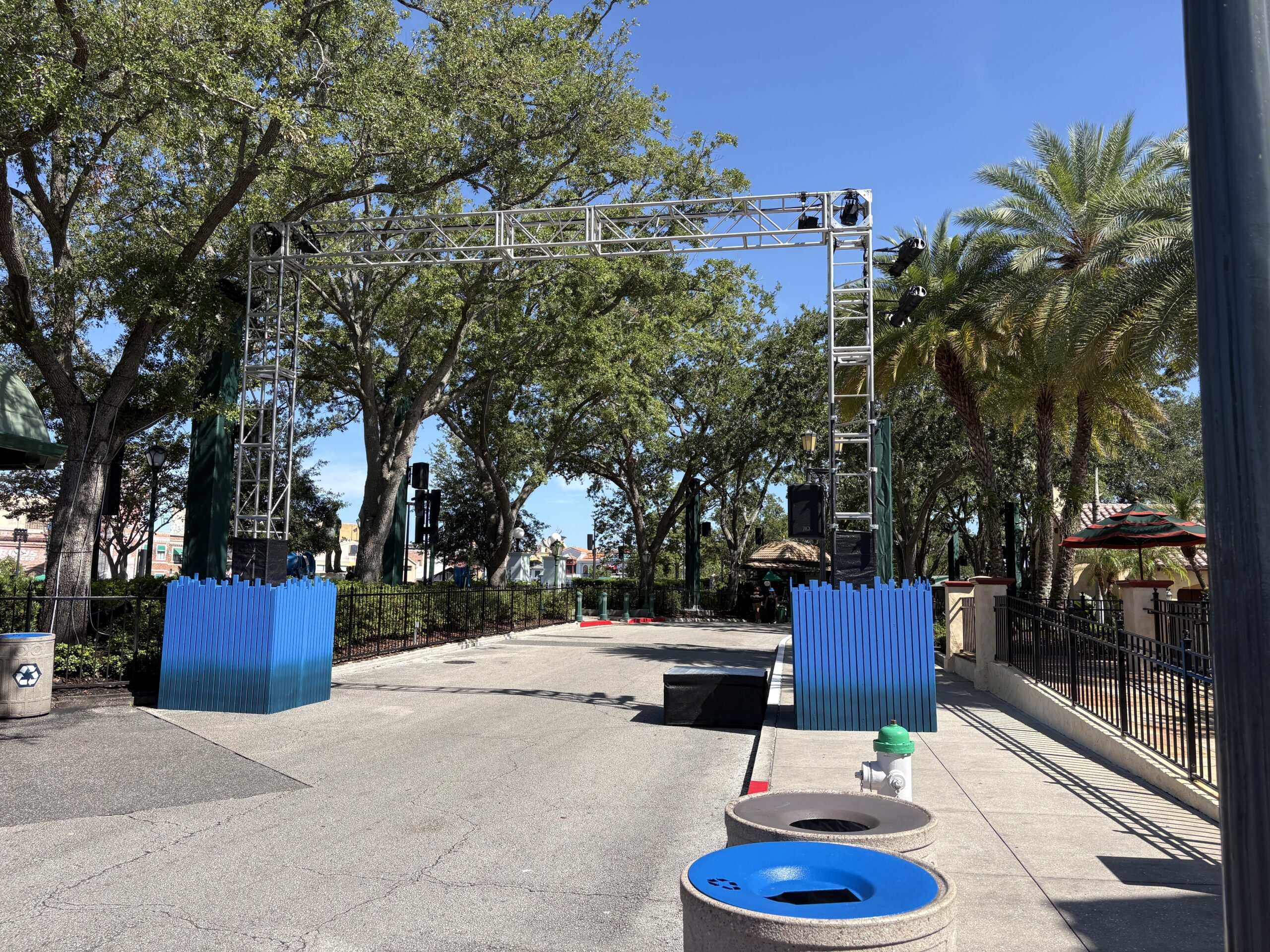 Between Hollywood and DreamWorks Land is what may be the FORTNITEMARES scare zone. Trusses are at the entrance to the zone, with blue fence-like walls around their bases. A small platform is on the ground next to one of the walls.