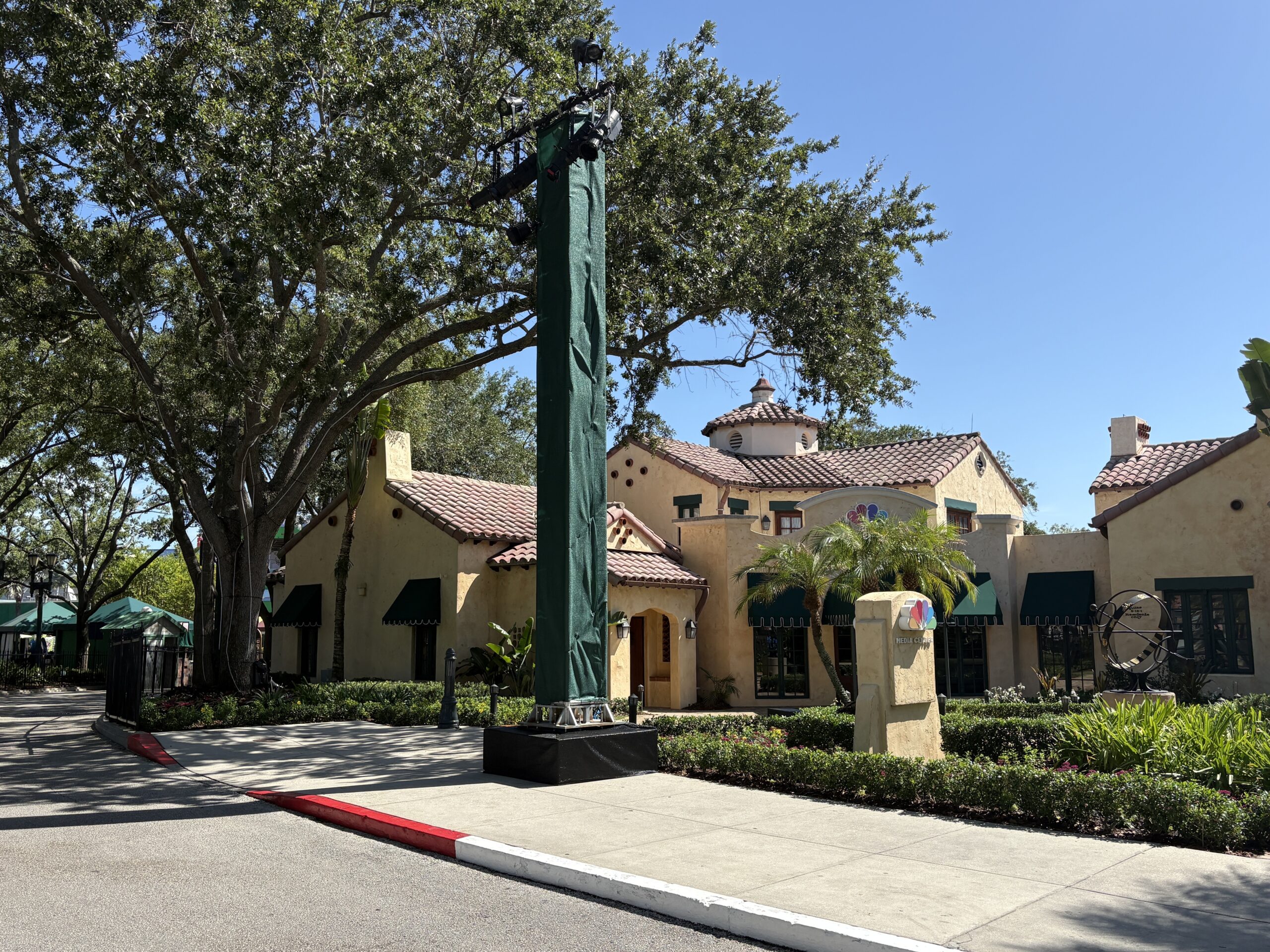 Two pillars wrapped in green scrim with mounted speakers and lights are further down the street. These may be covered with more theming later.