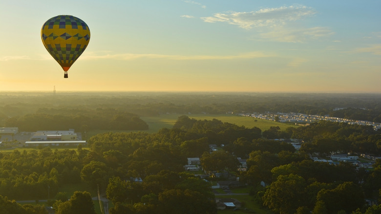 Yellow hot air balloon flying over trees, meadows, over Zephyrhills, Florida at sunset