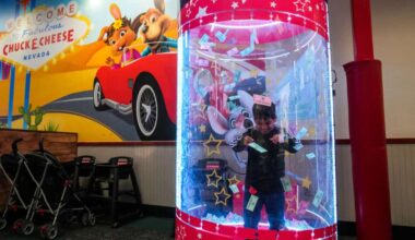 Smiling boy catching prize tickets in the Ticket Blaster at Chuck E. Cheese.