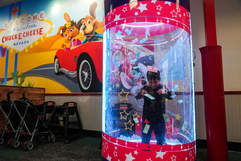 Smiling boy catching prize tickets in the Ticket Blaster at Chuck E. Cheese.