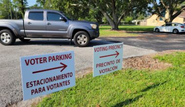 On a day with modest voter turnout, a truck drives into a voting precinct with signs pointing to the polling location.