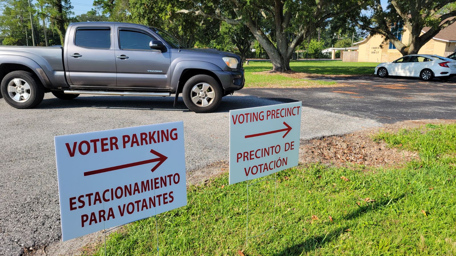 On a day with modest voter turnout, a truck drives into a voting precinct with signs pointing to the polling location.