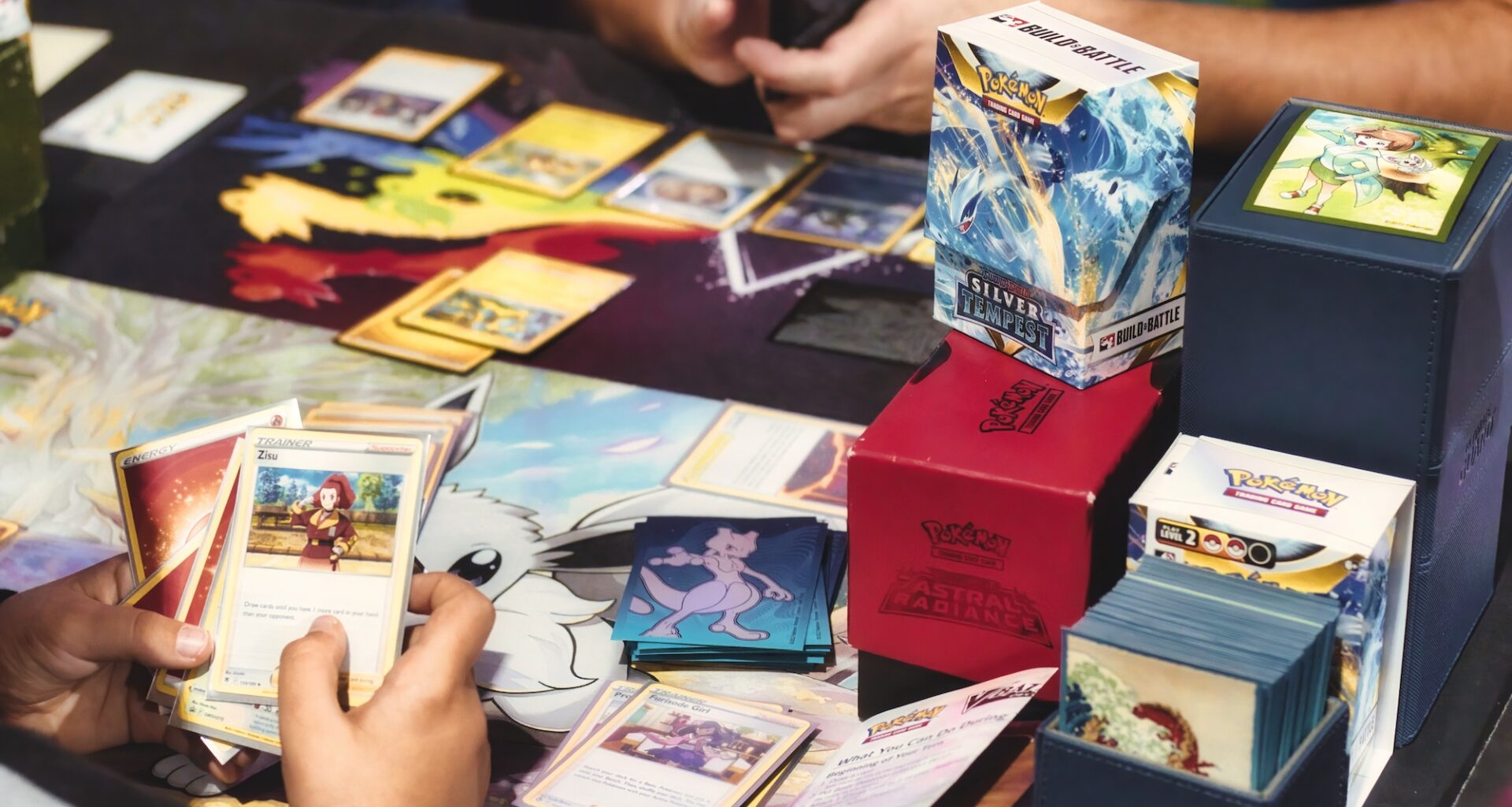 photo of two people playing with Pokemon trading cards on a table