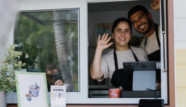 two people wave with glee at a bakery RV window