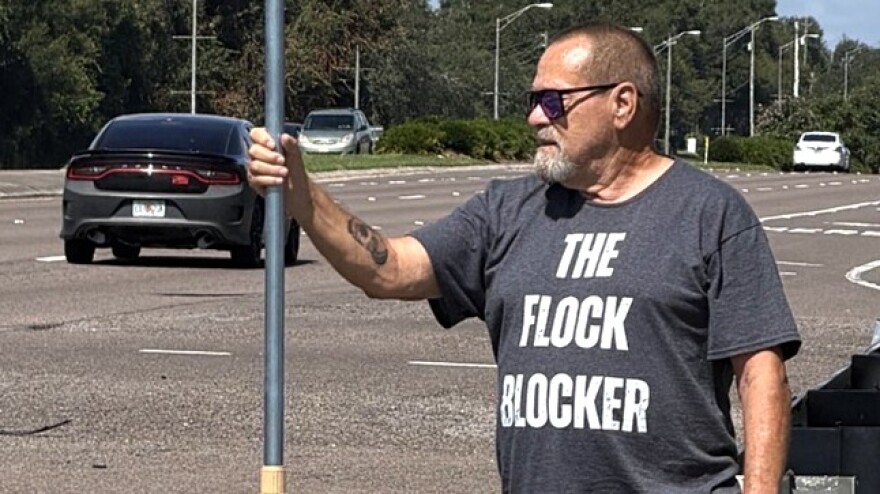 Carl Gunn, knowns as the “Flock Blocker,” has been using a sign on a long pole to cover up Flock cameras, which are automated license plate readers that also records vehicle details such as make, model, color, bumper stickers used by police.